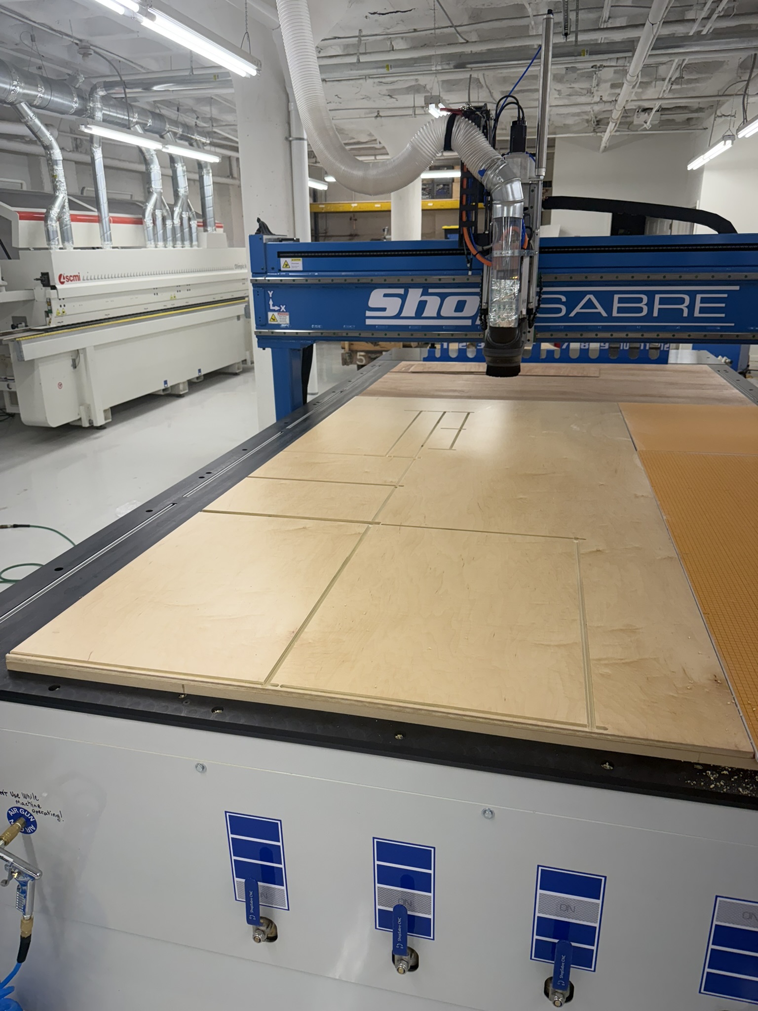 ShopSabre CNC router with sheet material on the cutting bed inside the HNE millwork shop