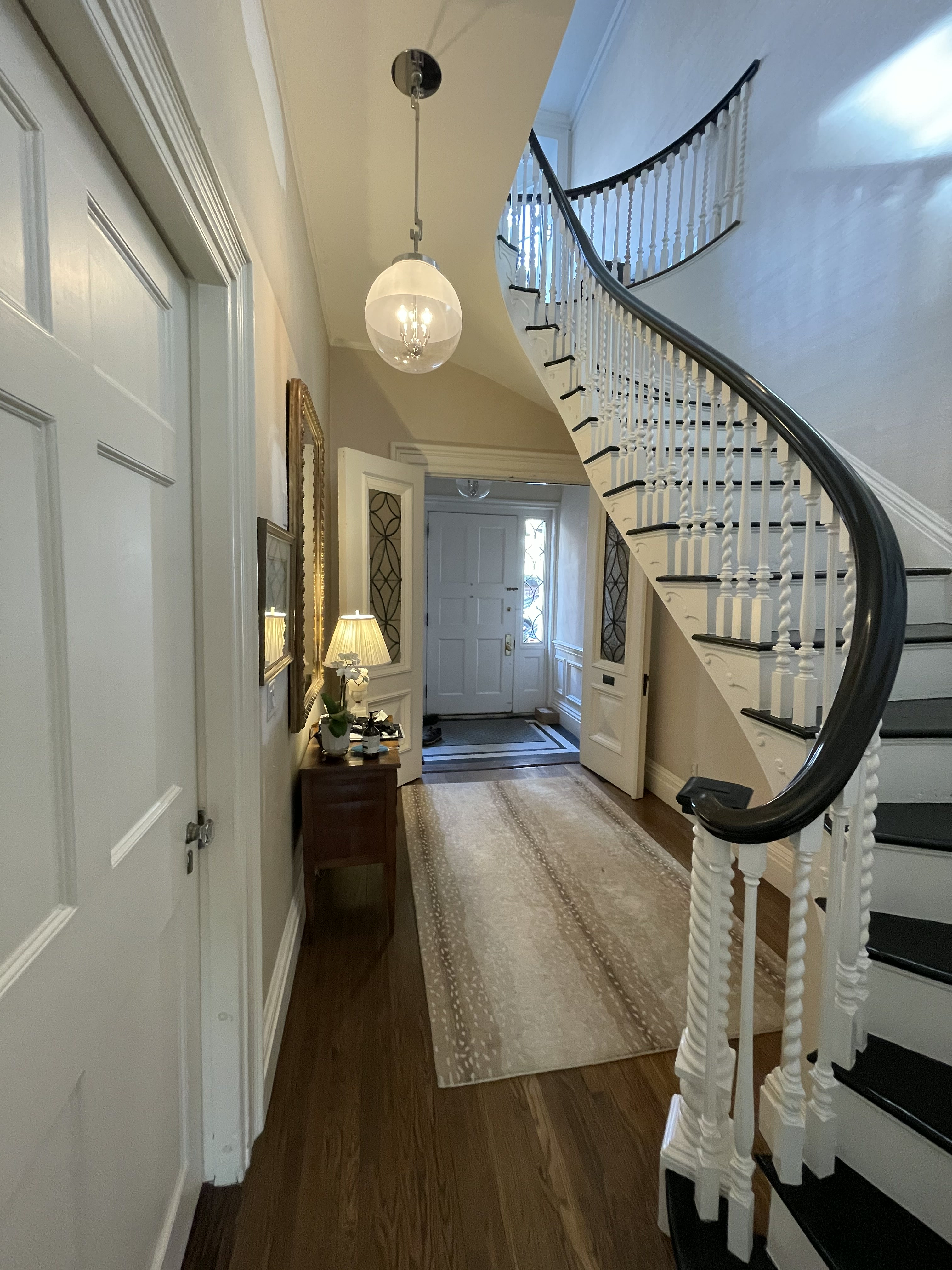 Sweeping dark handrail and white turned balusters above a paneled entry hall