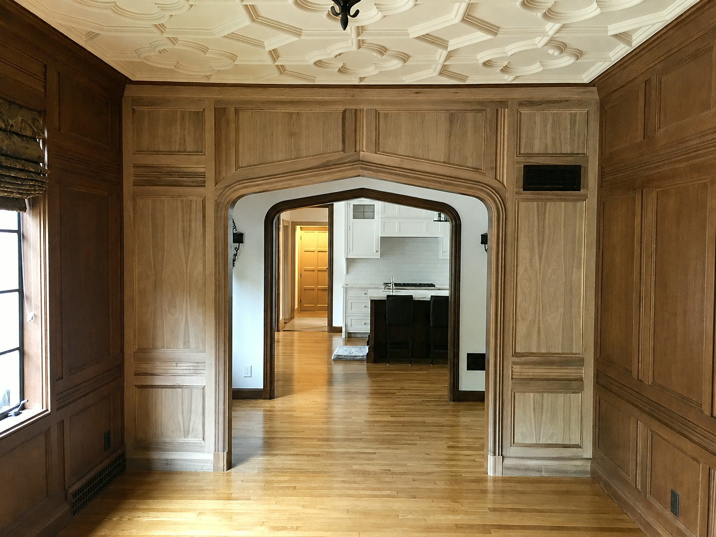 Wood wall paneling framing a shaped archway beneath an ornamental ceiling