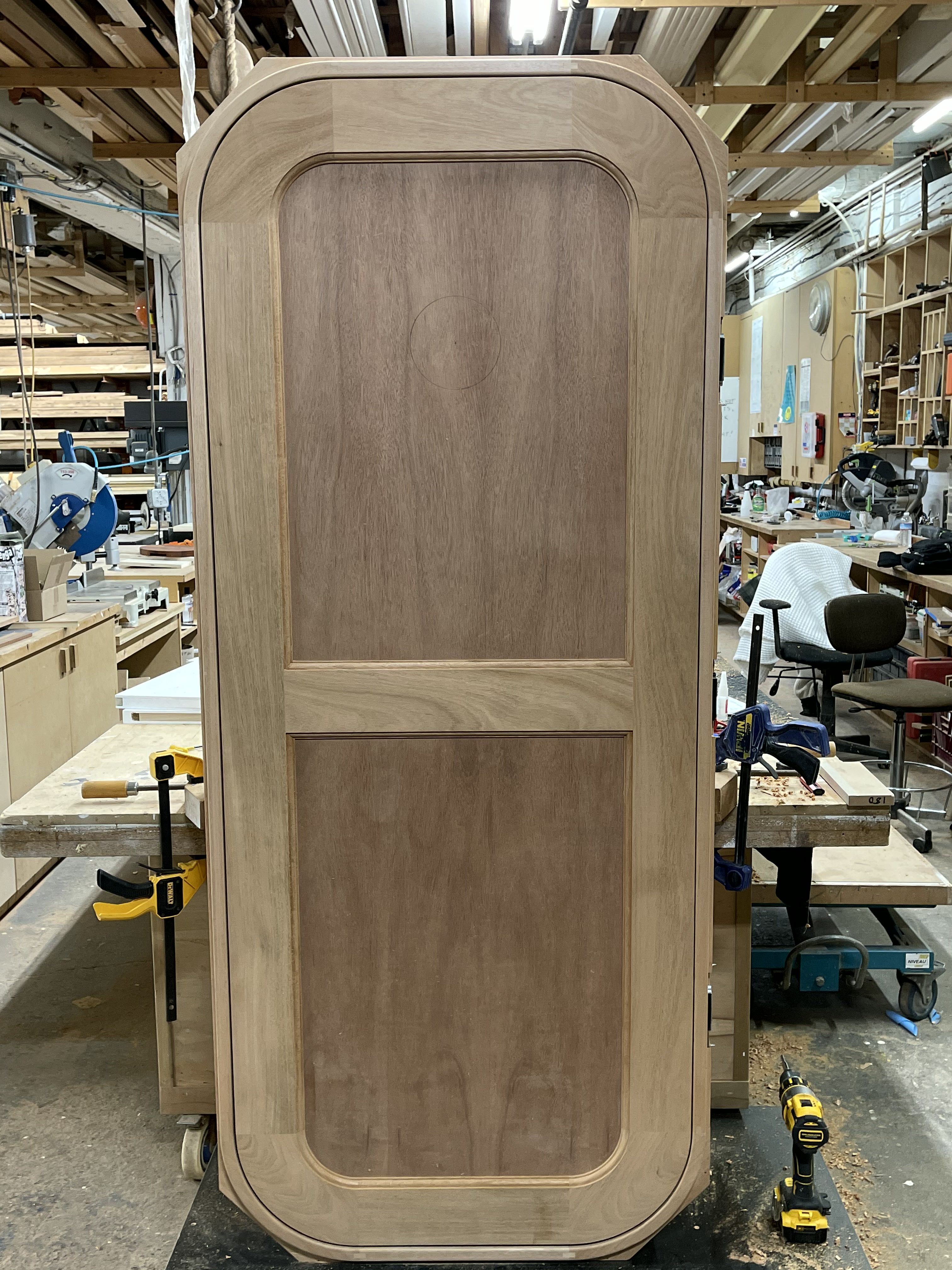 Unfinished wood panel door with rounded corners and matching frame on the shop bench